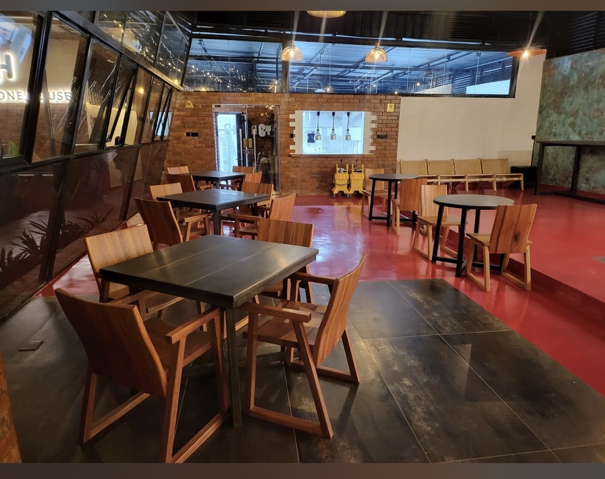 Interior dining room with handcrafted wooden chairs, exposed brickwork and warm string lighting